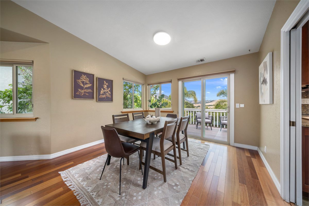 Sunlight pouring through spotless glass sliders onto a dining room, with palms and hills beyond