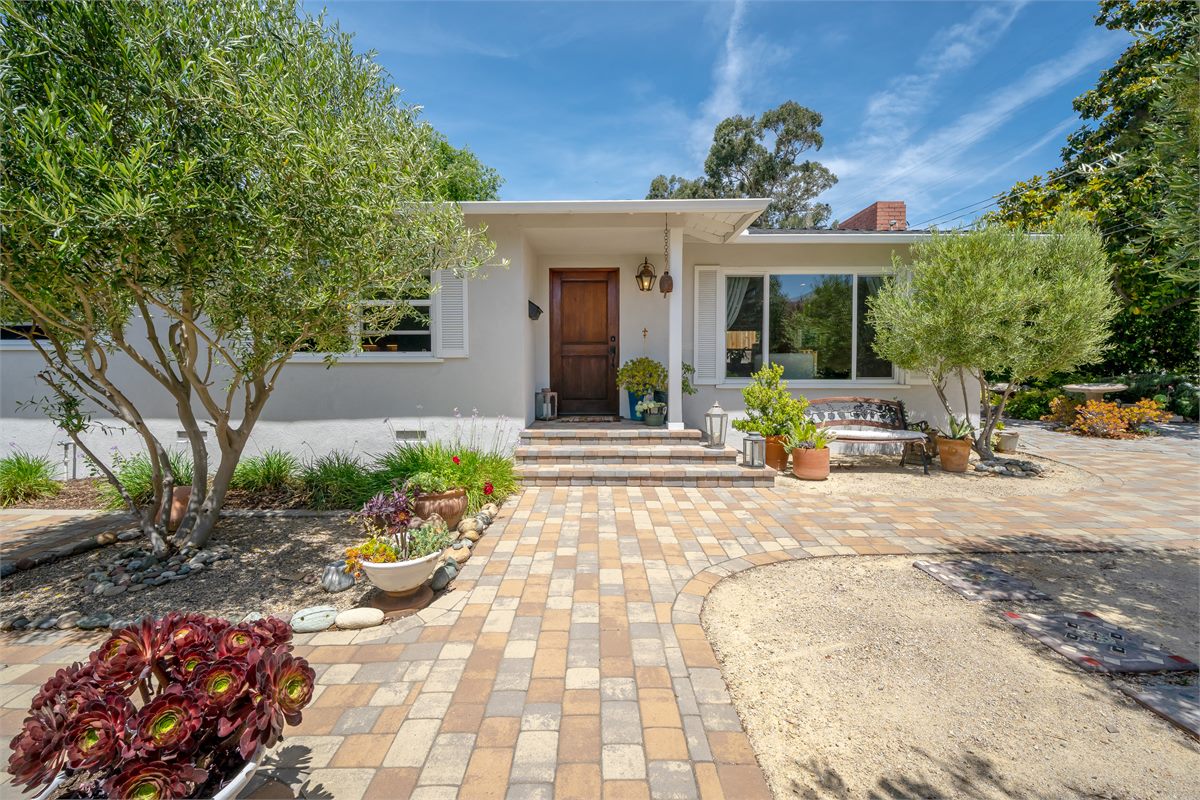 A freshly washed paver walkway and clean front entry framed by olive trees